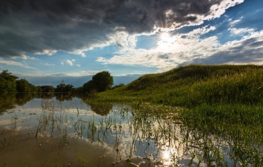 Doğal nehir üzerinde uğursuz fırtınalı gökyüzü