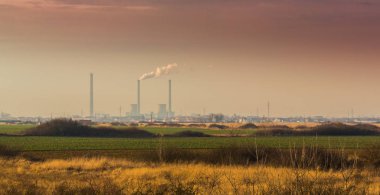Bitki duman kömür destekli yığınları ve endüstriyel cityscape, günbatımı renkleri üzerinde profilli hava kirliliği