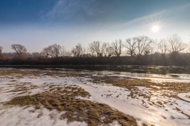 Donmuş nehir ve buz ile kış manzarası kum tepeleri, soğuk güneşli bir günde kaplı.