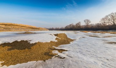 Donmuş nehir ve buz ile kış manzarası kum tepeleri, soğuk güneşli bir günde kaplı.