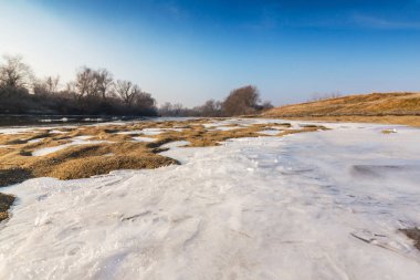 Donmuş nehir ve buz ile kış manzarası kum tepeleri, soğuk güneşli bir günde kaplı.