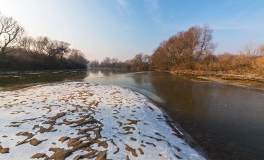 Donmuş nehir ve buz ile kış manzarası kum tepeleri, soğuk güneşli bir günde kaplı.