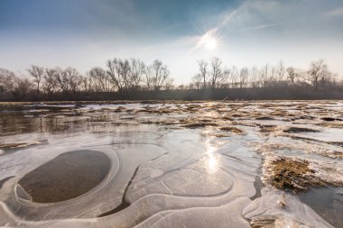 Donmuş nehir ve buz ile kış manzarası kum tepeleri, soğuk güneşli bir günde kaplı.