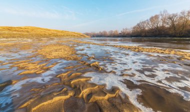 Donmuş nehir ve buz ile kış manzarası kum tepeleri, soğuk güneşli bir günde kaplı.