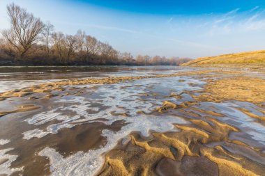 Donmuş nehir ve buz ile kış manzarası kum tepeleri, soğuk güneşli bir günde kaplı.