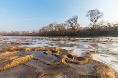 Donmuş nehir ve buz ile kış manzarası kum tepeleri, soğuk güneşli bir günde kaplı.