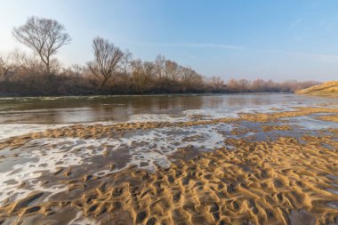 Donmuş nehir ve buz ile kış manzarası kum tepeleri, soğuk güneşli bir günde kaplı.