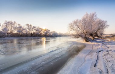 Güzel kış manzarası kapsamındaki frost, donmuş nehir boyunca ağaçlar ile