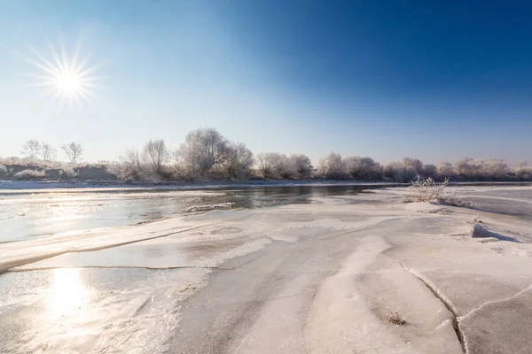 Güzel kış manzarası kapsamındaki frost, donmuş nehir boyunca ağaçlar ile