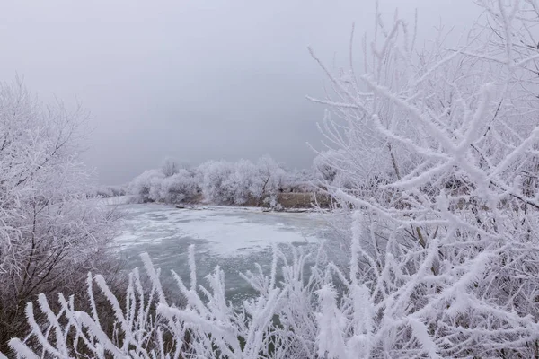 Hermoso paisaje de invierno con árboles cubiertos de heladas, a lo largo del río congelado y nubes de tormenta — Foto de Stock