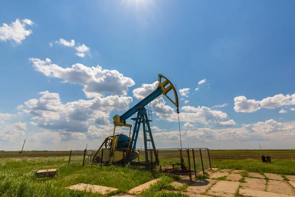 Pozo de petróleo y gas en funcionamiento en el campo petrolífero europeo, perfilado en el cielo azul con nubes cúmulos — Foto de Stock