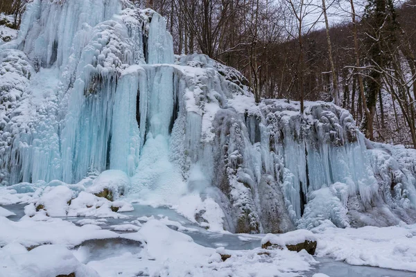 Wilder Fluss, wunderschöne gefrorene Wasserfälle und frischer Schnee in einem Bergwald, an einem kalten Wintertag — Stockfoto