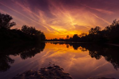 Muhteşem sonbaharda günbatımı bulutlu gökyüzü yansıması ile vahşi Nehri Panoraması