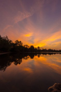 Muhteşem sonbaharda günbatımı bulutlu gökyüzü yansıması ile vahşi Nehri Panoraması