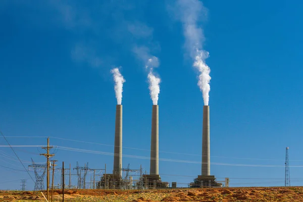 Heavy smoke from coal-powered power plant stacks, profiled on blue sky