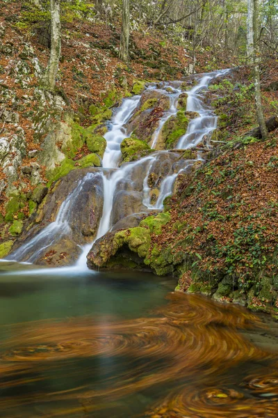 Beautiful waterfalls and golden autumn foliage in a mountain forest, on a bright, sunny, day