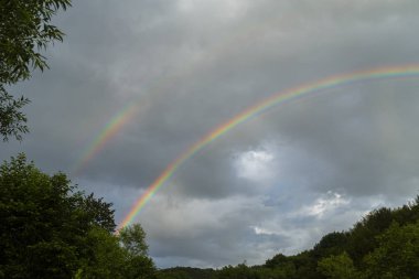Güzel dağ manzarası ve gökkuşağı fırtınalı gökyüzünde yağmurdan sonra