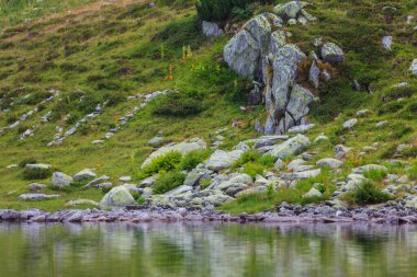 Transilvanya Alplerinde yaz manzarası, granit kayalar, buzul gölü ve fırtına bulutları