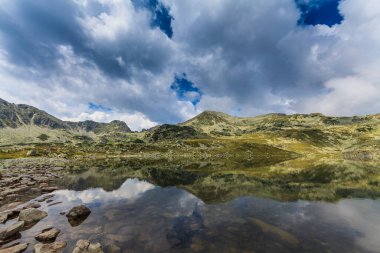 Transilvanya Alplerinde yaz manzarası, granit kayalar, buzul gölü ve fırtına bulutları