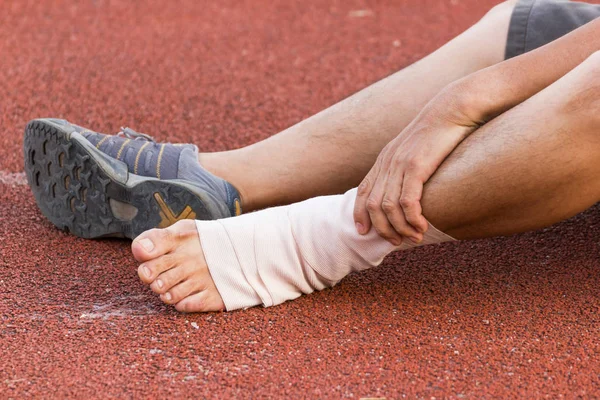 Erkek atlet sıkıştırma bandaj bir futbolcu, spor yaralanmaları ayak bileği yaralanması üzerine uygulama.