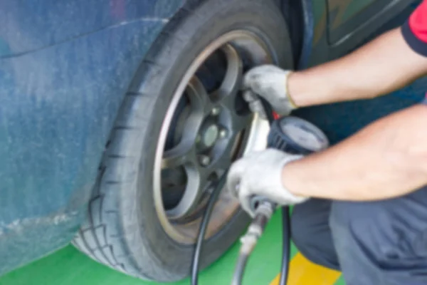 Blurred Man Filling air into a car tire to increase pressure at car service center