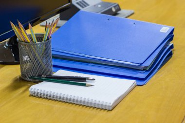 Pencils in cup, Pen, Notebook, Blue document file on Wooden desk in a meeting room clipart