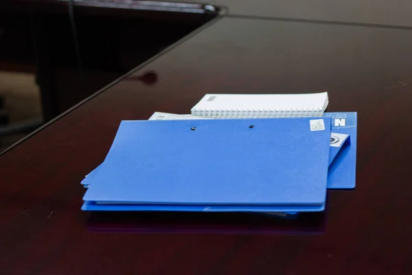 会議室の茶色の机の上の契約とガラスの青いファイルフォルダの保持 — ストック写真