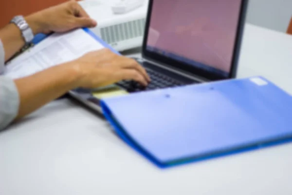 blurred man hand holding files document and typing computer keyboard notebook in work office