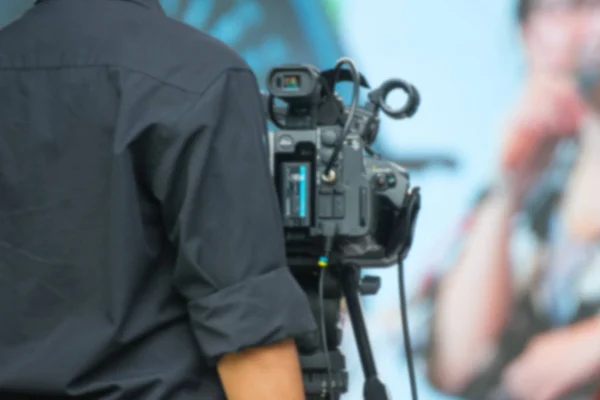 Blurred professional cameraman - covering on event with a video