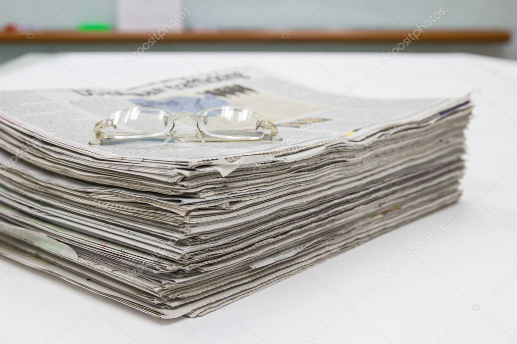 Closeup - Newspaper Stack on white table in office 