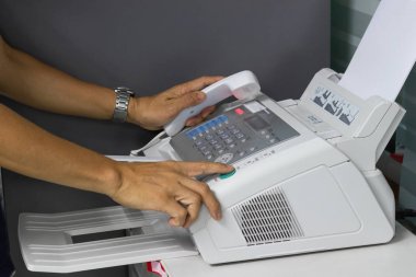 Elini adam ofiste bir faks makinesi kullanarak. İş kavramı 