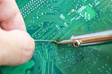 Teknisyenler elektronik tamir için bir lehimleme demir kullanıyor 