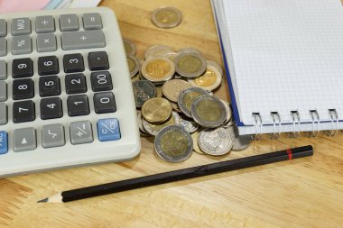Ofisteki ahşap masa üzerinde hesap makinesi olan para yığını, gelir, gelir ve giderler hesaplama kavramı.