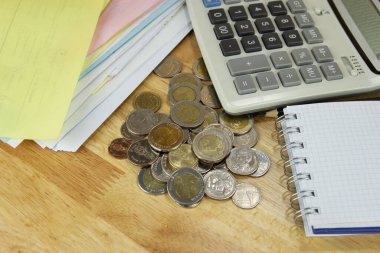 Ofisteki ahşap masa üzerinde hesap makinesi olan para yığını, gelir, gelir ve giderler hesaplama kavramı.