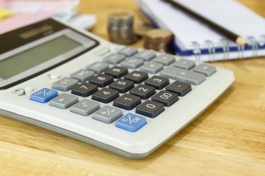Ofisteki ahşap masa üzerinde hesap makinesi, masrafların, gelirlerin ve giderlerin hesaplanması kavramı.