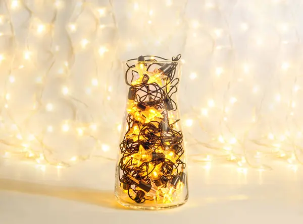 Guirlanda de Natal com lâmpadas em forma de estrela em um vaso transparente de vidro, decoração festiva de férias — Fotografia de Stock