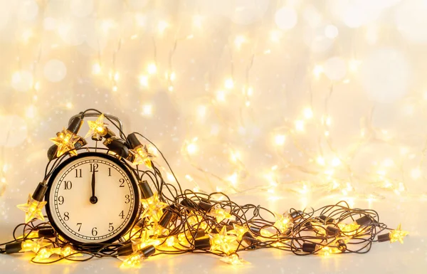 Новогодние будильники, завернутые в праздничную звездную гирлянду. Полночь . — стоковое фото
