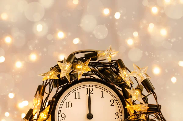 Reloj despertador de Año Nuevo envuelto en una guirnalda de estrellas festivas. Medianoche . — Foto de Stock