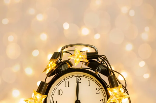 Reloj despertador de Año Nuevo envuelto en una guirnalda de estrellas festivas. Medianoche . — Foto de Stock