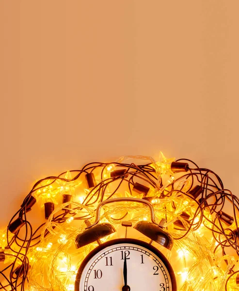 Новогодний будильник в окружении праздничной звездной гирлянды на желтом фоне . — стоковое фото