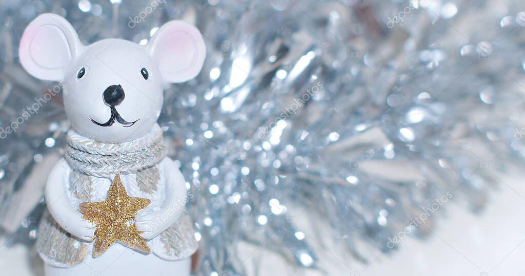 white festive toy of mouse or rat on the white background with silver shiny tinsel behind.