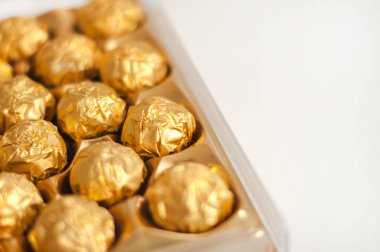 Altın folyoya sarılı bir kutu yuvarlak şeker. Beyaz arka plan. Lüks yemekler..