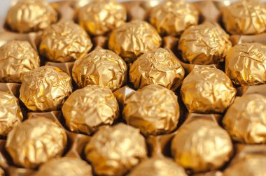 Altın folyoya sarılı yuvarlak şekerler, yaklaşın. Beyaz arka plan. Lüks yemekler..