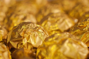 Altın folyoya sarılı bir kutu yuvarlak şeker. Makro atış. Lüks yemekler..