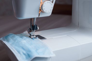 Evdeki dikiş makinesine tıbbi maske dikiyorum..
