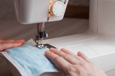 Evdeki dikiş makinesine tıbbi maske dikiyorum..