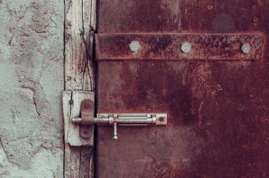 Kilitli paslı, eski püskü metal bir kapı.