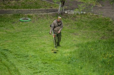 14 Mayıs 2020, Voronezh, Rusya. Bahçe çim biçme makinesiyle çim biçen bir adam. Rus konut hizmetleri.