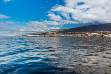 Canlı sahne ve derin mavi suları bir yat görüldüğü gibi Tenerife Batı kıyı şeridi. Uyuyan Teide yanardağı arka planda görülebilir. Birçok turizm tatil kıyı şeridi gözden kaçırmak..