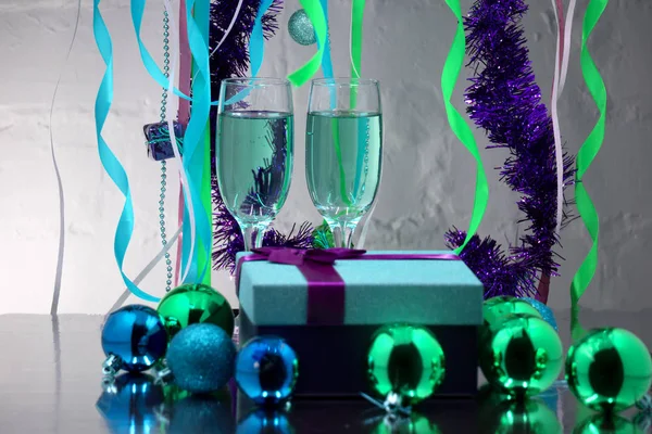 Bicchieri con champagne frizzante, regalo, decorazioni natalizie su sfondo blu — Foto Stock